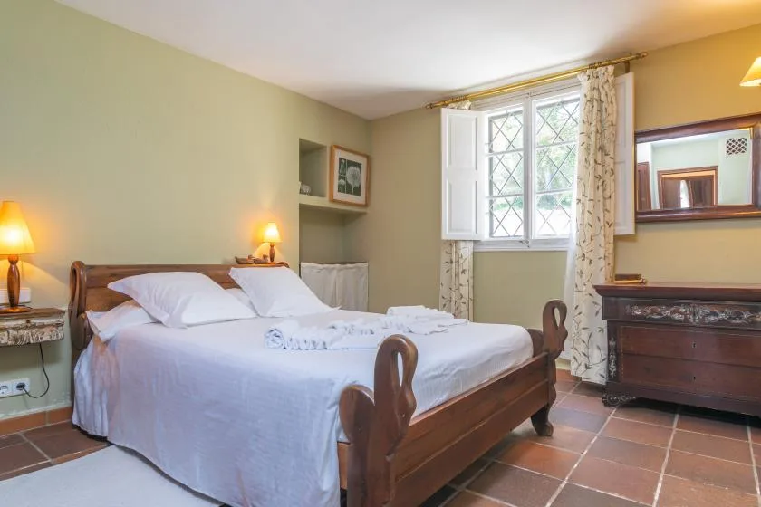 A bedroom with a wooden bed beside a bright window.