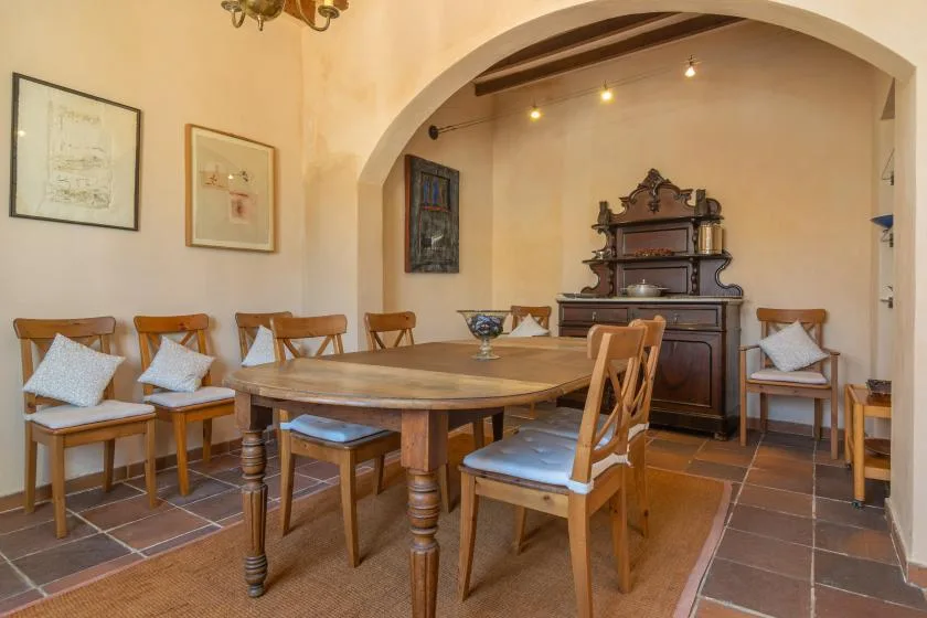 A dining room with a wooden table and chairs beneath a wide arch.