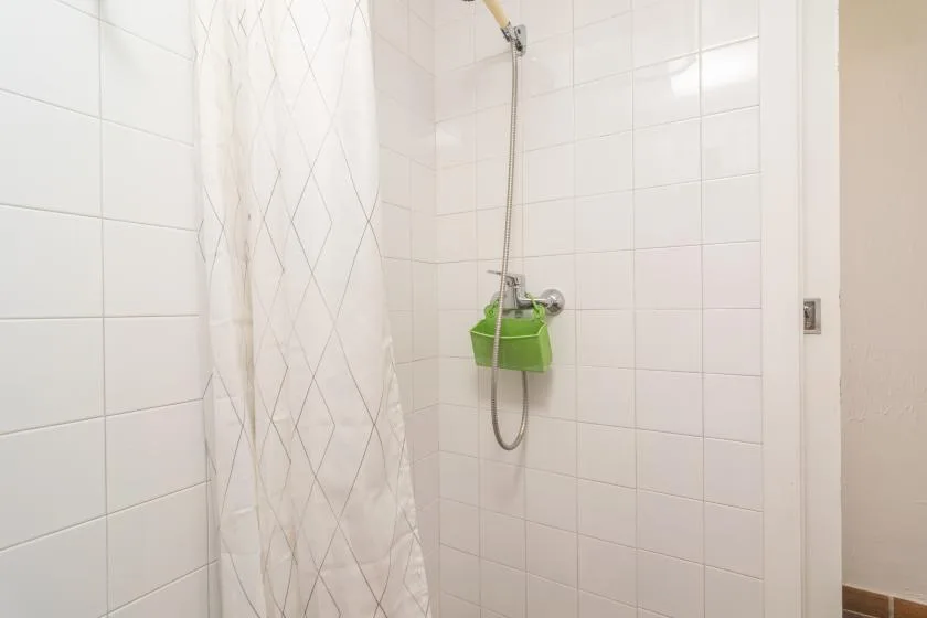 A tiled bathroom shower area with a curtain and wall-mounted showerhead.