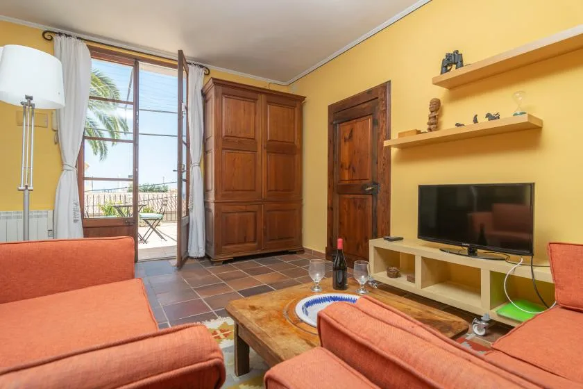 A living room with orange seating, a television, and a wooden coffee table.