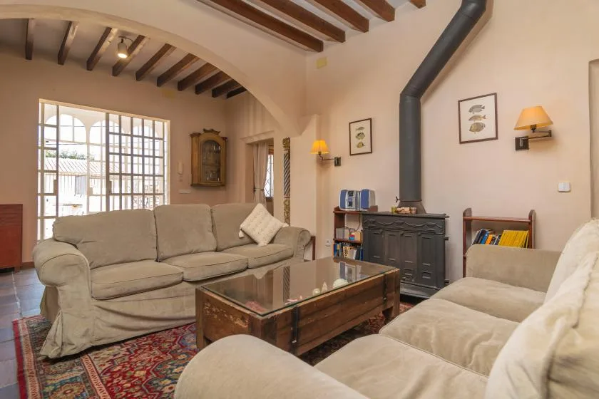 A living room with upholstered seating, a coffee table, and exposed ceiling beams.