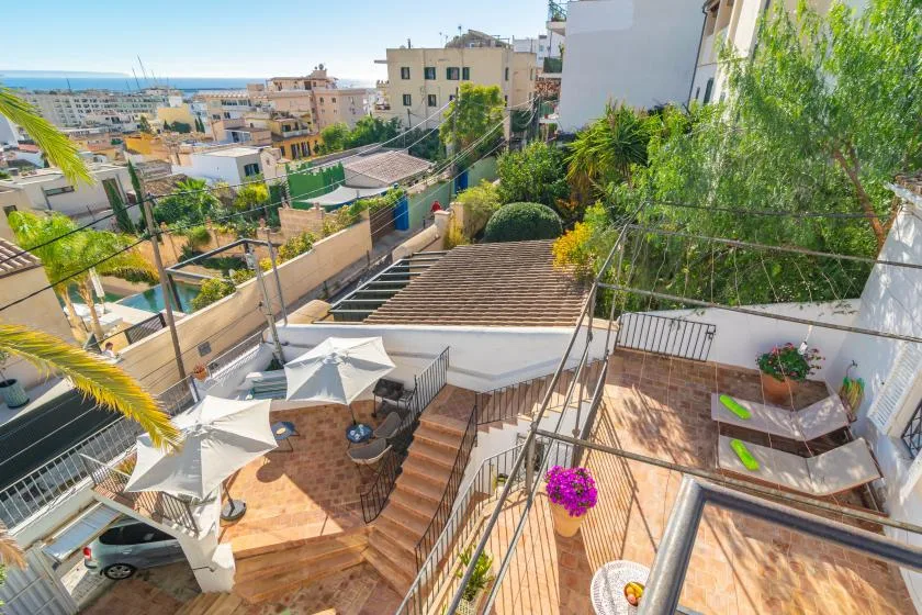A terraced outdoor patio overlooks surrounding buildings and a distant stretch of sea.