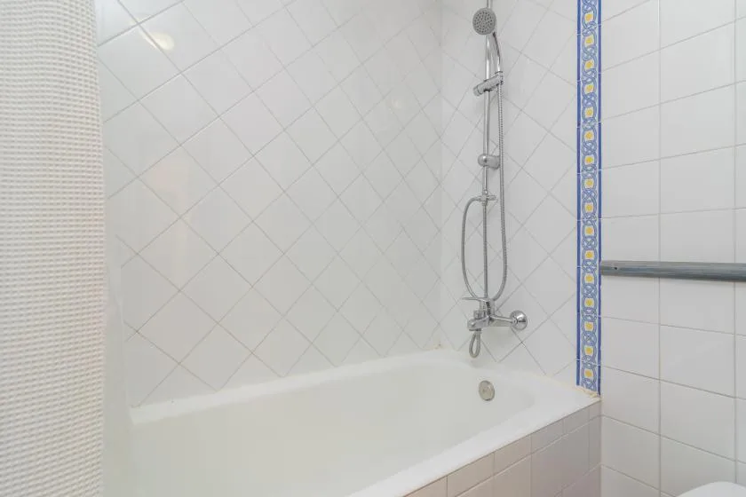 A tiled bathroom with a bathtub and wall-mounted shower.