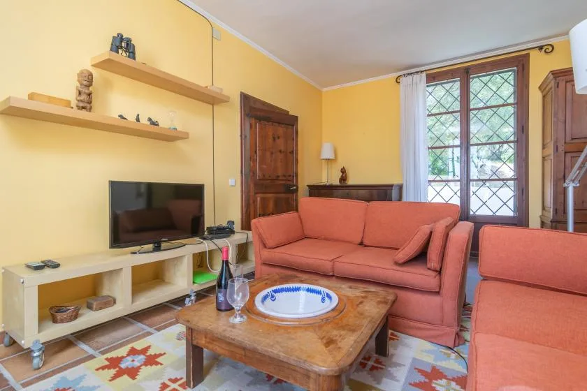 A living room with coral-colored seating, a television, and a wooden coffee table.