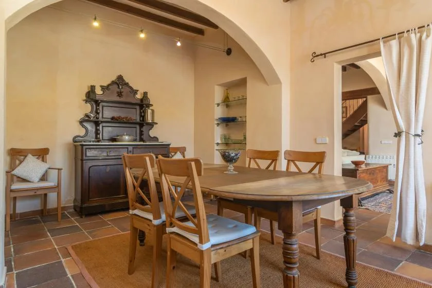 A dining room with a large wooden table and chairs beneath an arched ceiling.