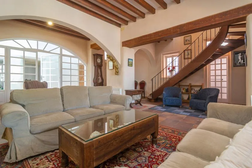 A spacious living room with seating, a glass coffee table, and a staircase.