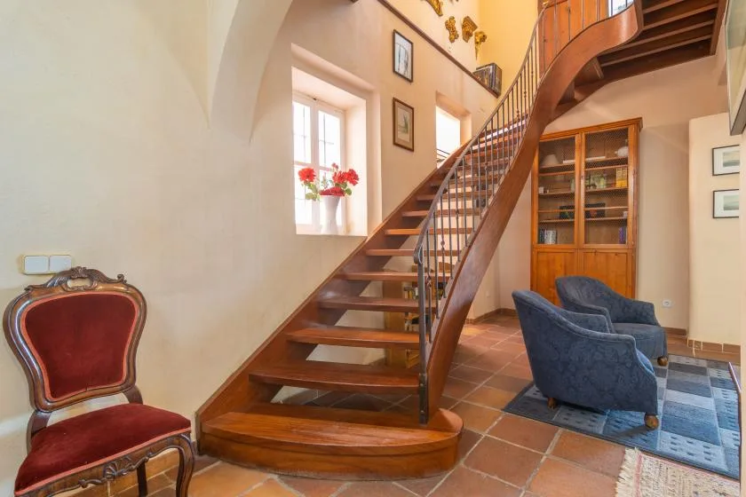 A bright interior stair hall with a curved wooden staircase and seating.