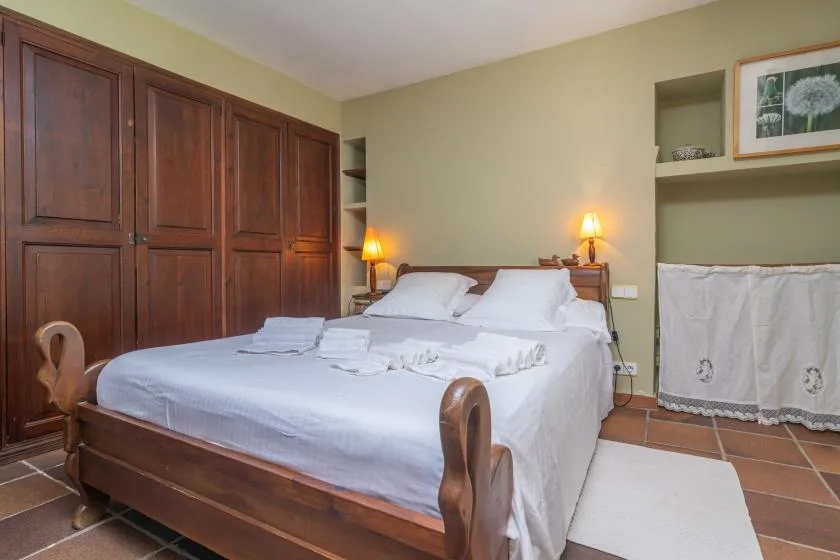A bedroom with a large bed, dark wooden wardrobes, and bedside lamps.