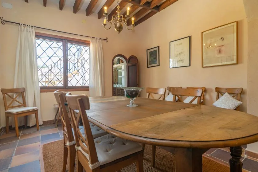 A dining room with a large wooden table, chairs, and a chandelier.