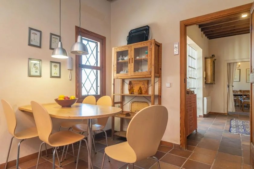 A dining area with a round table, chairs, and a wooden display cabinet.