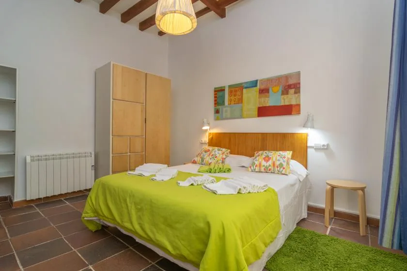 A bedroom with a double bed, colorful bedding, and a green bedspread.