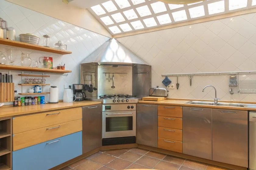 A bright kitchen with wooden counters, open shelves, and a central stove.