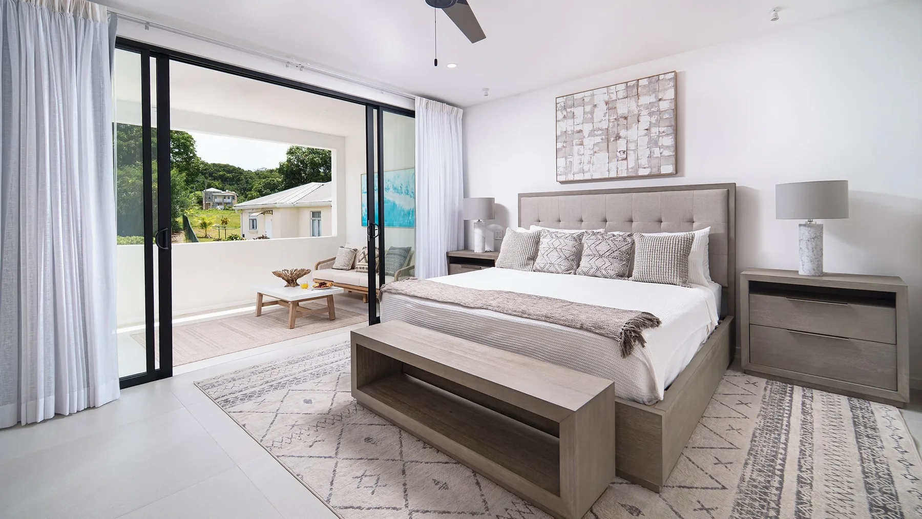 Un dormitorio luminoso con una cama grande y puertas corredizas de vidrio que dan a un balcón.