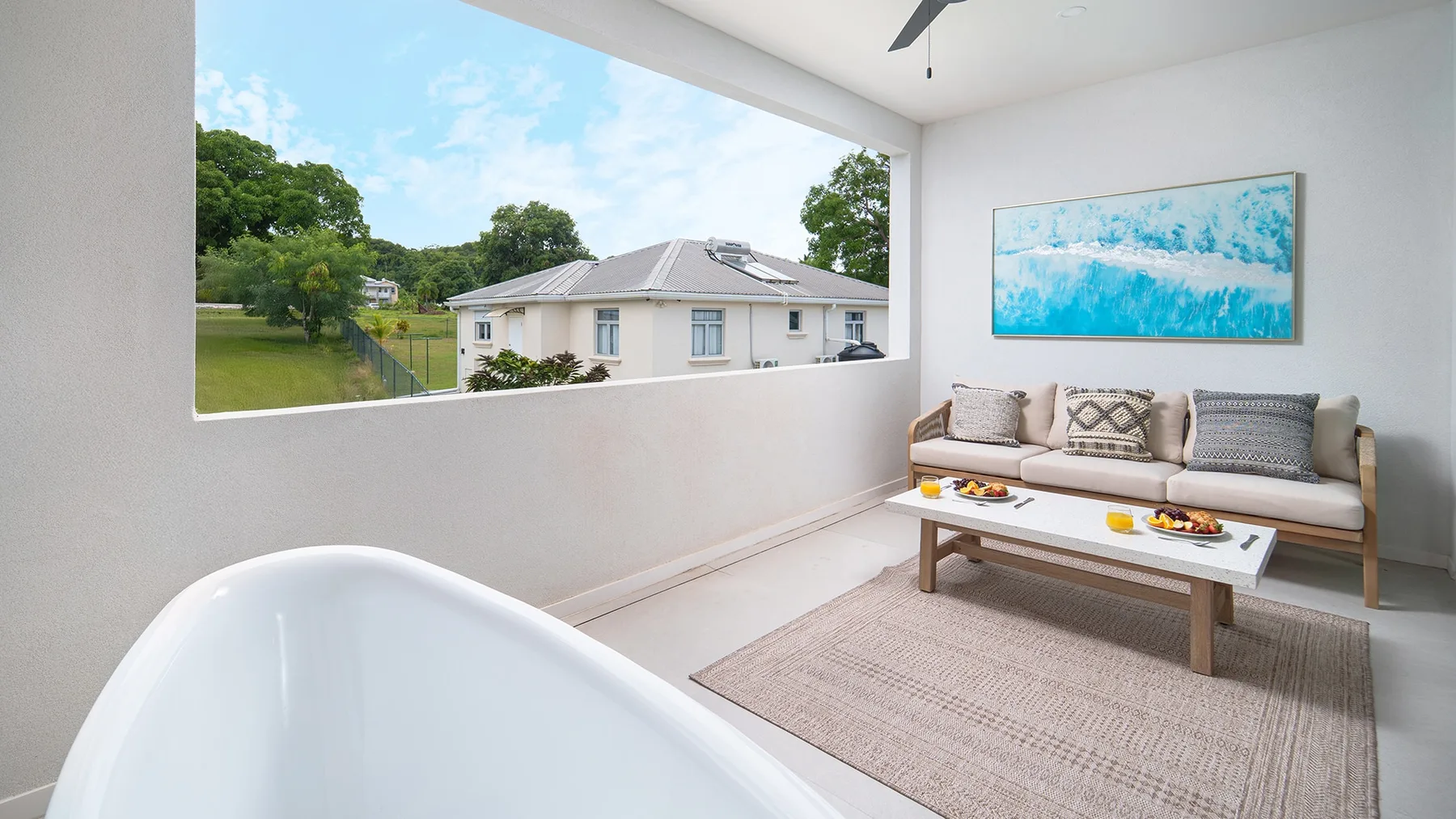 A covered outdoor seating area with a sofa, coffee table, and large open window.