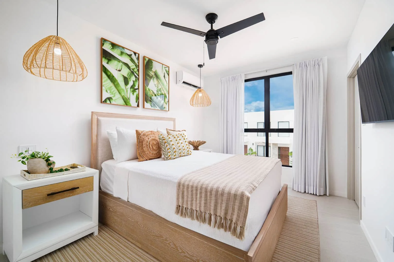 Un dormitorio luminoso con una cama, lámparas colgantes tejidas y una ventana grande.