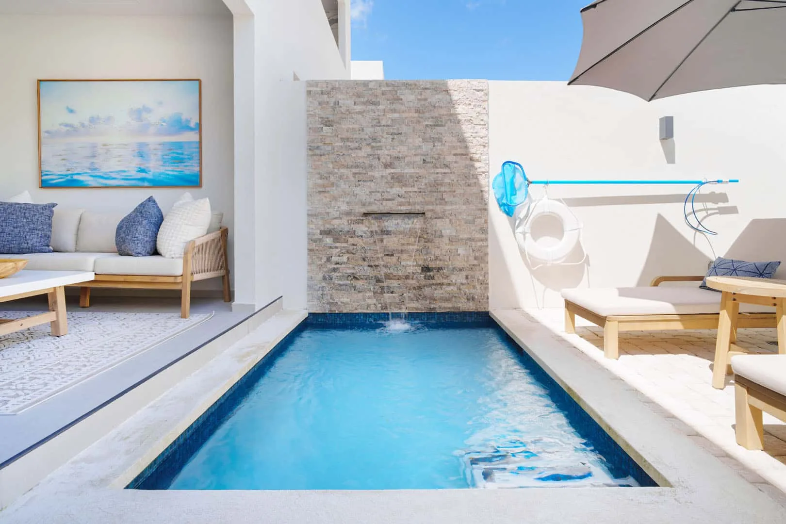 Una pequeña piscina exterior queda entre una zona de estar y un patio soleado.