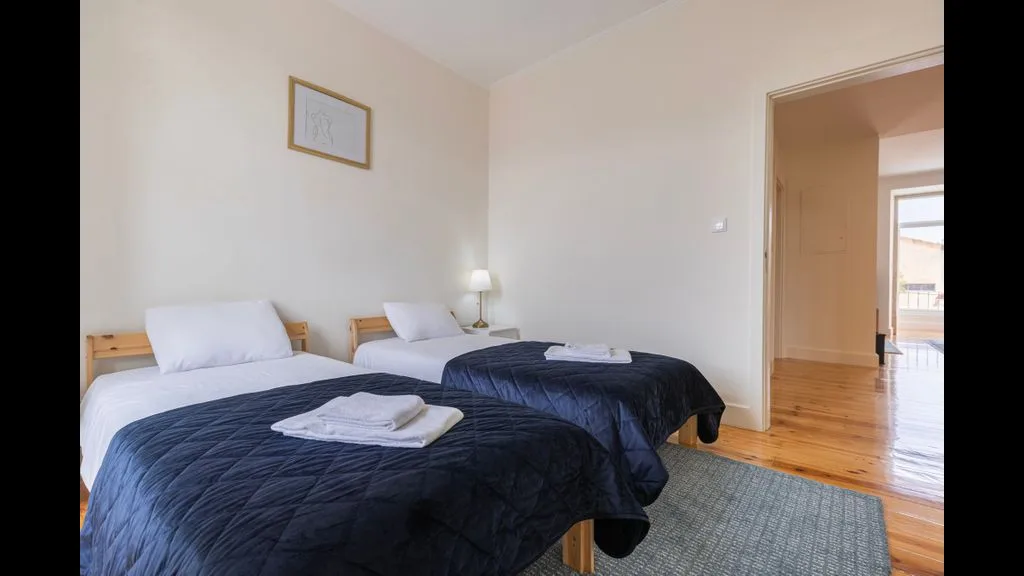 Un dormitorio con dos camas individuales y toallas dobladas sobre la ropa de cama.