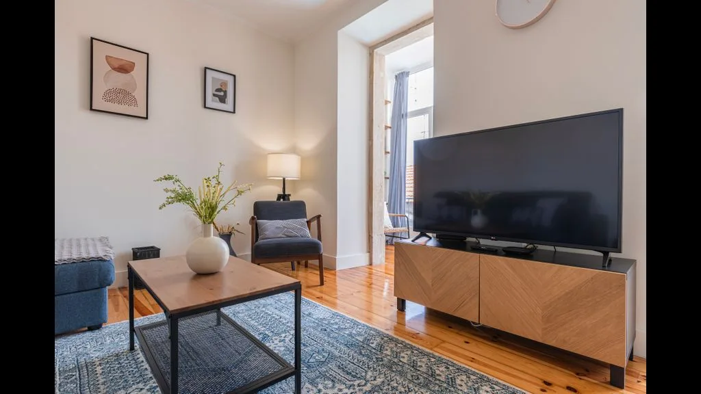 Una sala luminosa con televisor, asientos y una mesa de centro.