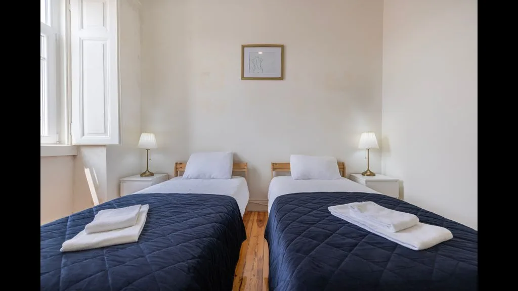 Un dormitorio con dos camas, ambas vestidas con ropa de cama azul oscuro.
