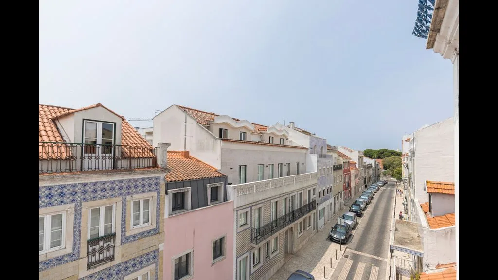 Una calle estrecha flanqueada por edificios de varias plantas y coches aparcados.