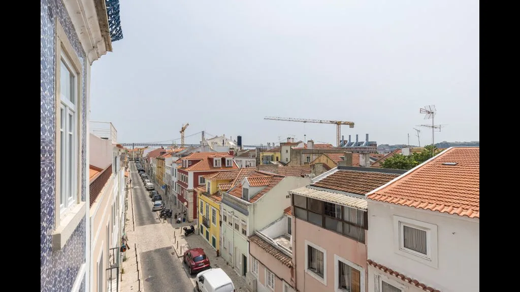 Una calle urbana estrecha flanqueada por edificios coloridos y tejados de tejas rojas.