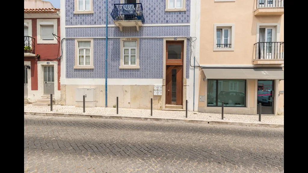 Escena callejera con fachadas de edificios contiguos y una calzada empedrada.