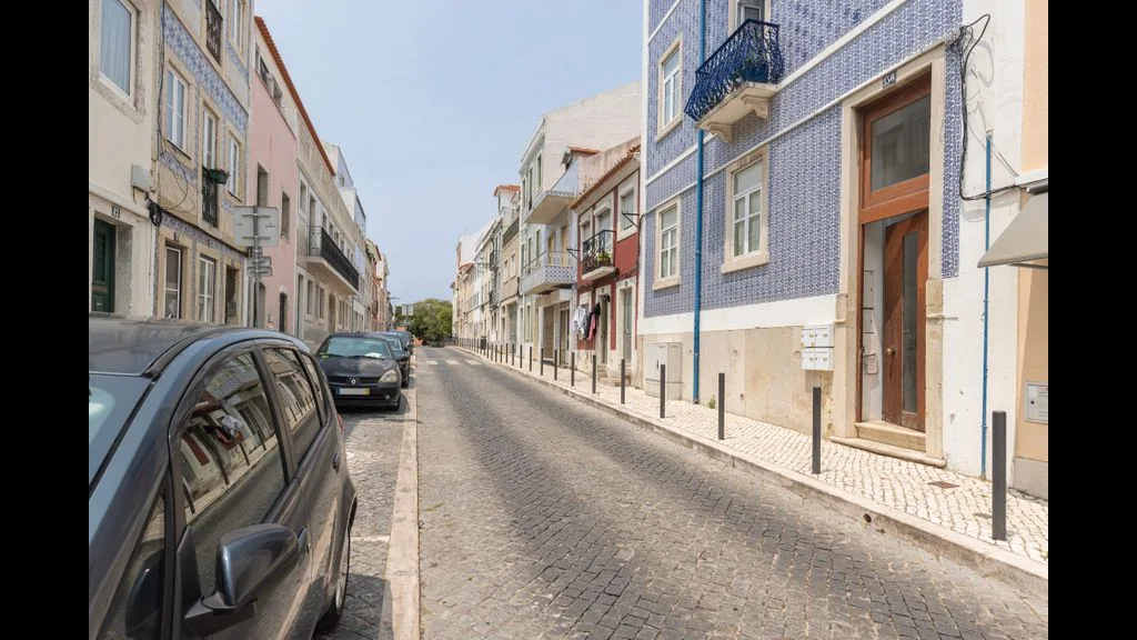 Una calle estrecha de adoquines flanqueada por edificios y coches estacionados.
