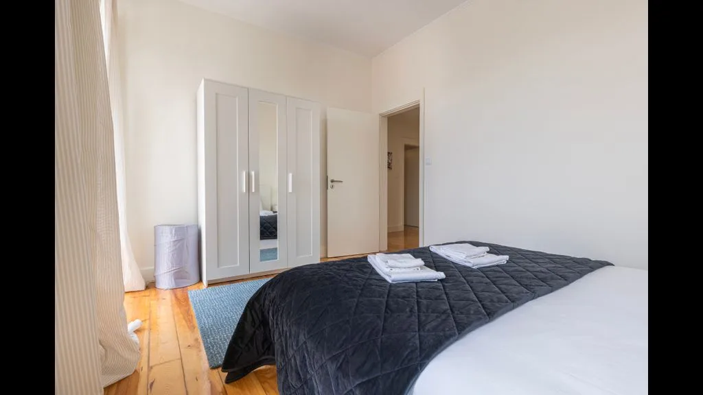 Un dormitorio con una cama cubierta con una colcha oscura y un armario.