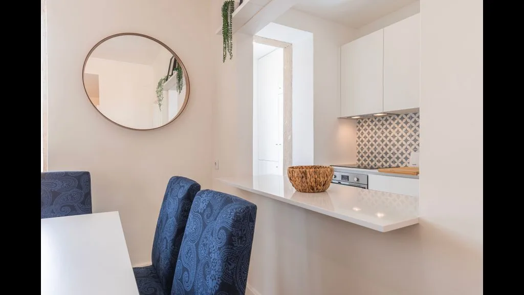 Un comedor luminoso se abre a una cocina compacta con una encimera blanca.