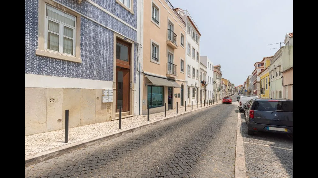 Una calle empedrada flanqueada por edificios de varias plantas y coches aparcados.