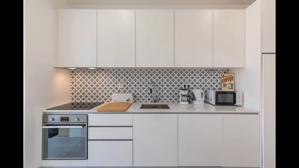 Una cocina moderna con armarios blancos y un salpicadero estampado.
