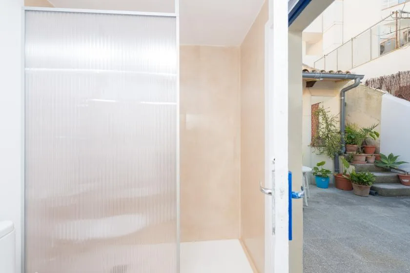 A shower area opens onto a small courtyard with potted plants.