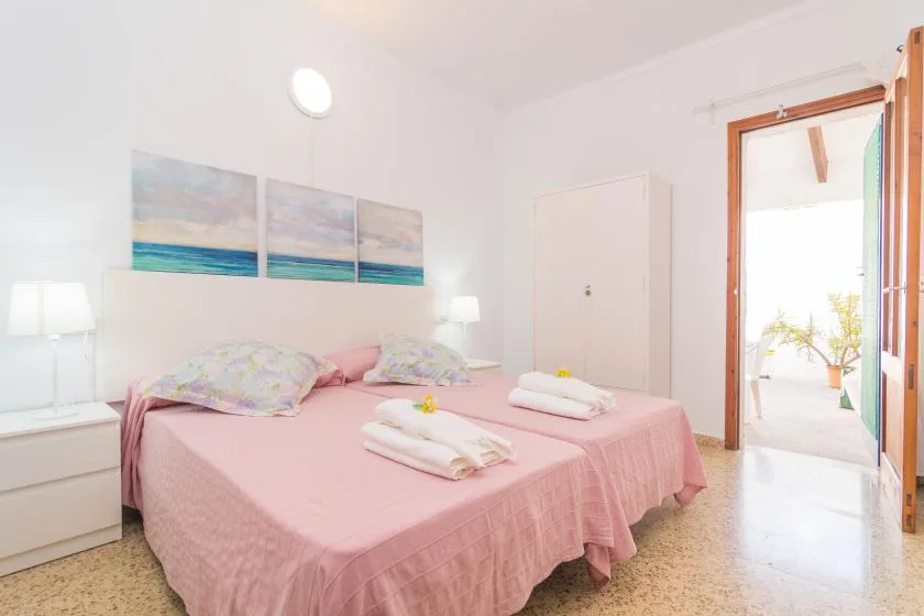 A bright bedroom with a pink bed and artwork above the headboard.
