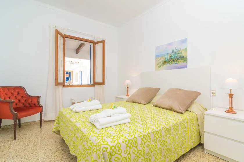 A bedroom with a bed covered in a bright patterned bedspread and pillows.