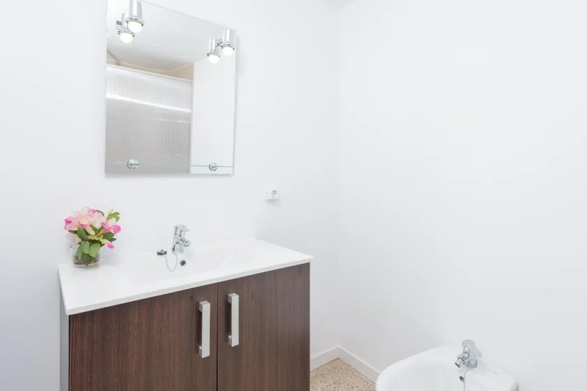 A bathroom vanity with a mirror and a bathtub in view.