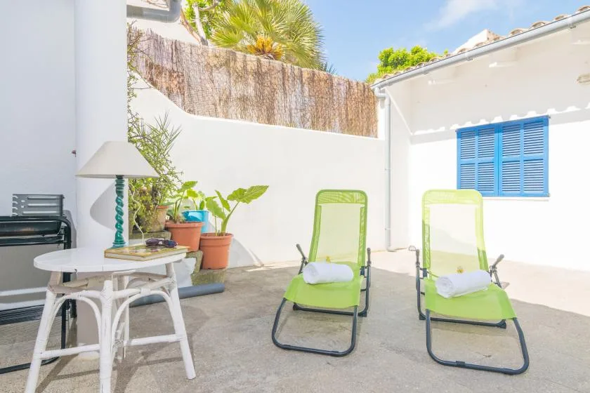 An outdoor patio with green lounge chairs and potted plants.