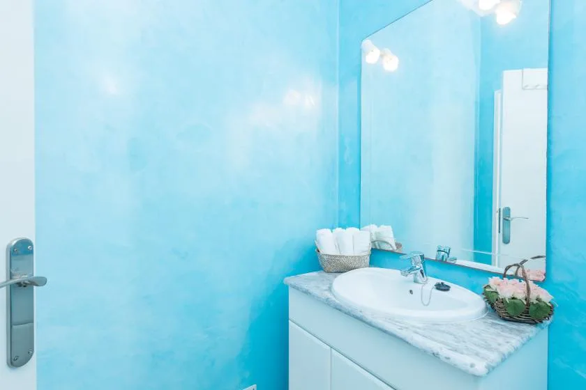 A bright bathroom with a sink vanity and large mirror.