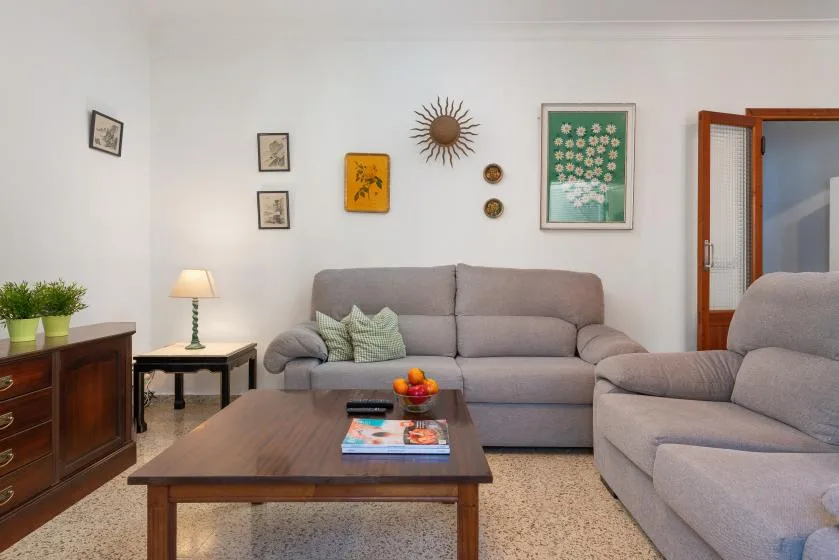 A living room with gray seating, a wooden coffee table, and framed wall art.