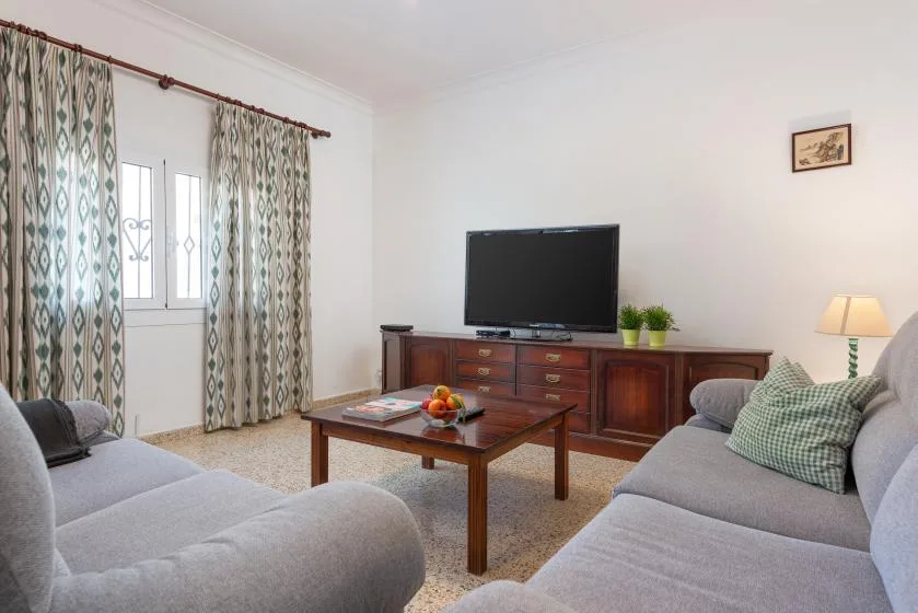 A living room with seating around a coffee table and television.