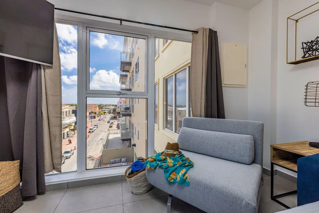 Unwind on your comfy sofa with a vibrant cityscape just beyond the windows, where the lively street below offers an inviting peek into the local neighborhood.