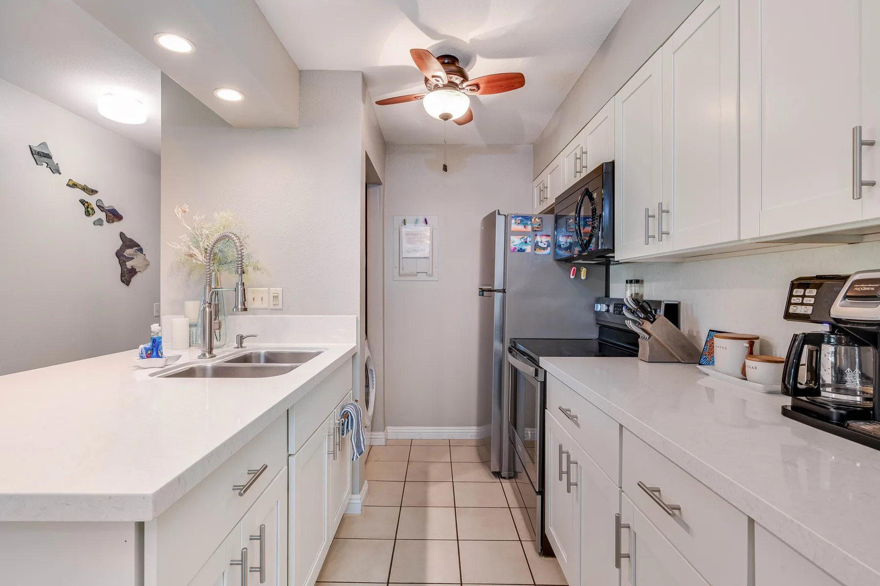 A bright kitchen with white cabinets, countertops, and stainless steel appliances.