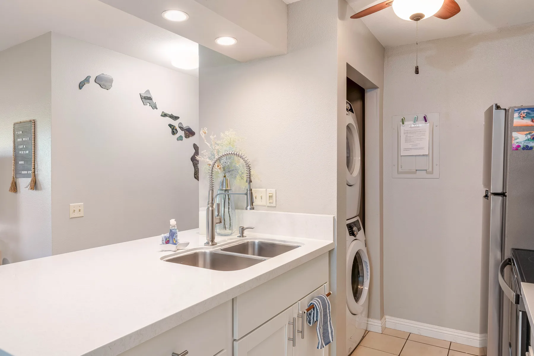 A laundry room with a countertop sink, stacked washer and dryer, and refrigerator.