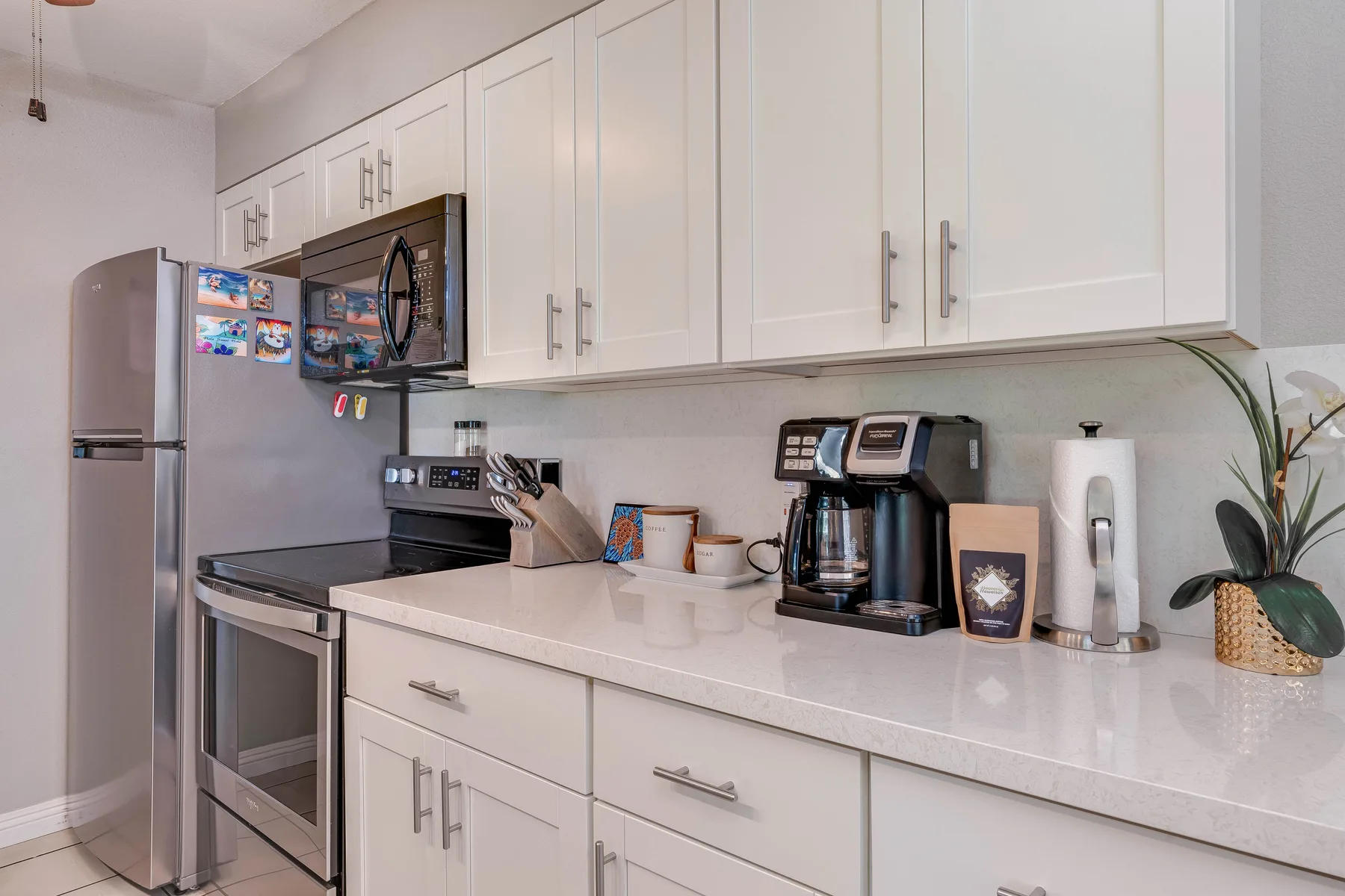 A bright kitchen counter with white cabinets and small appliances.