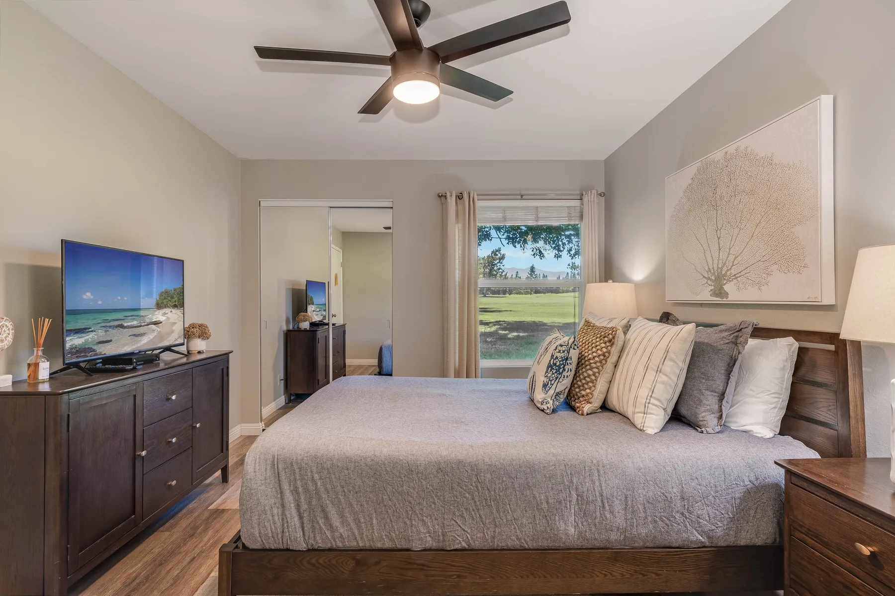 A bedroom with a large bed, bedside tables, and a television on a dresser.