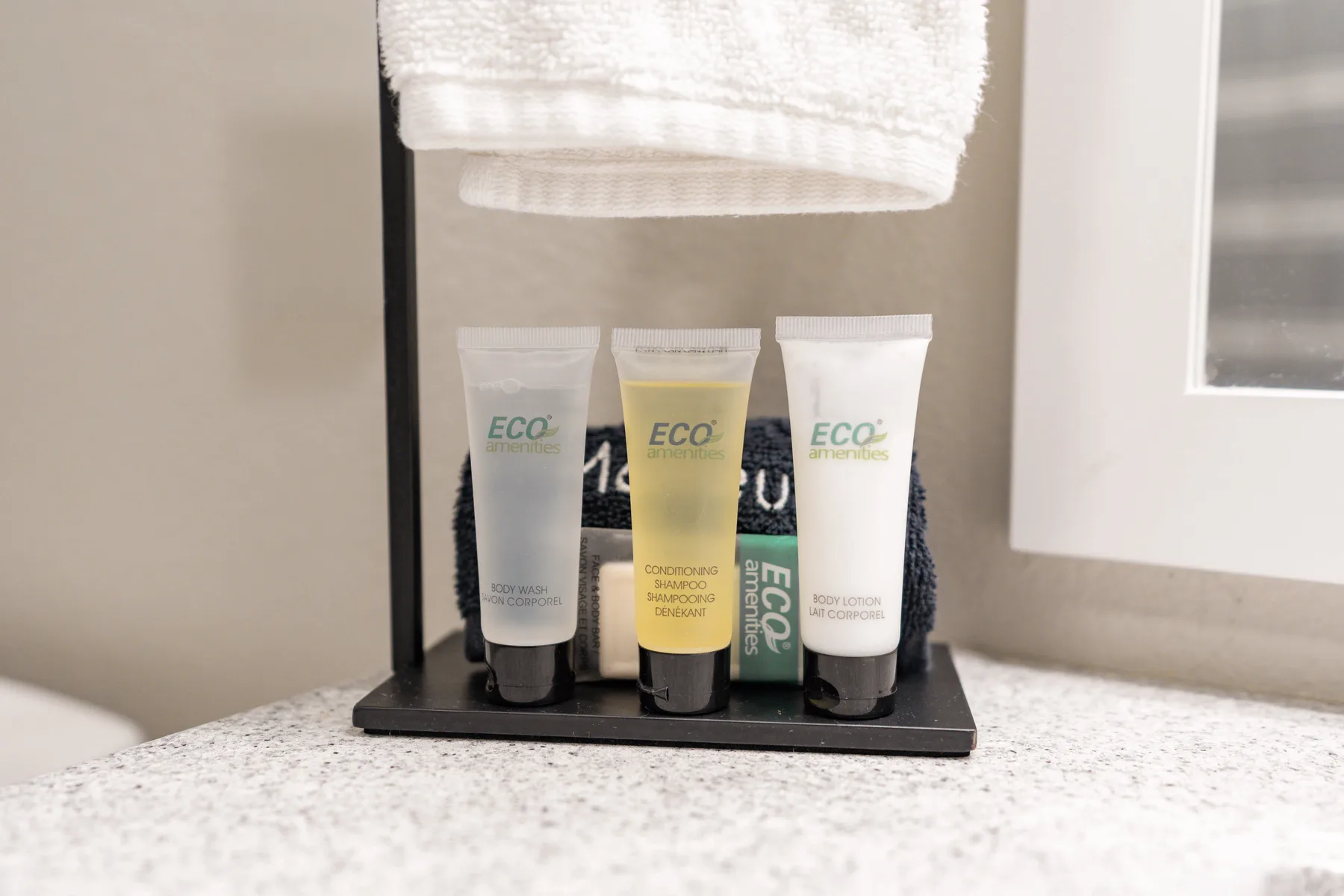 Bathroom toiletries sit on a counter beneath a folded towel.