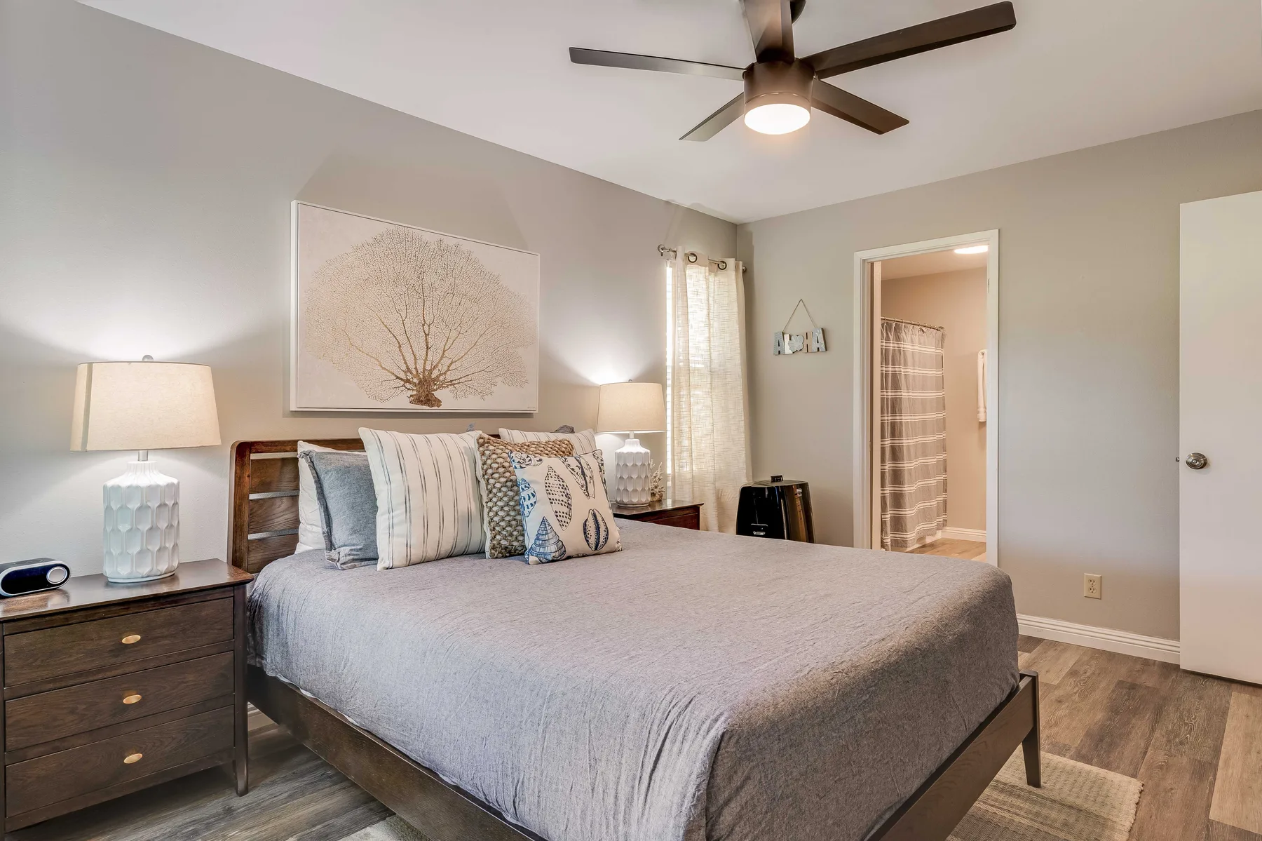 A bedroom with a neatly made bed and a ceiling fan.