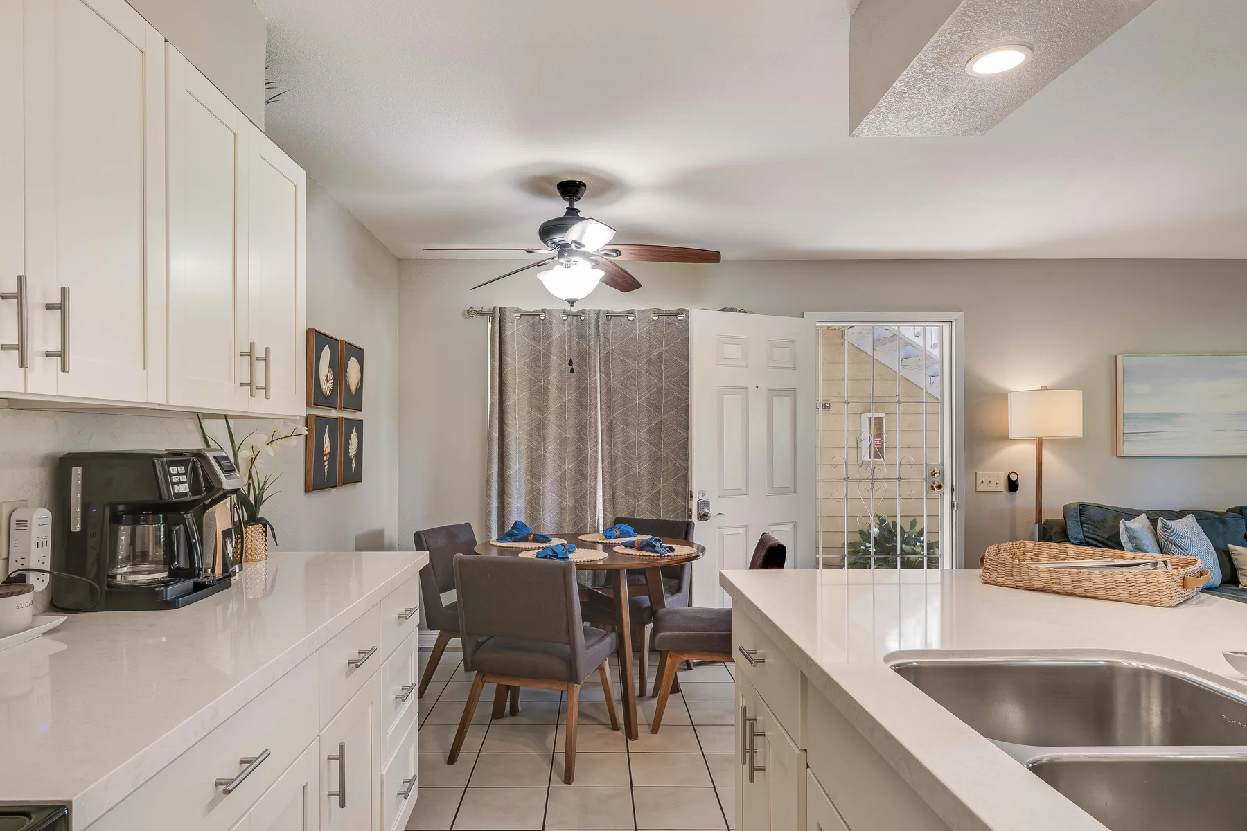 A bright kitchen and dining area with white counters and a table beside the patio doors.