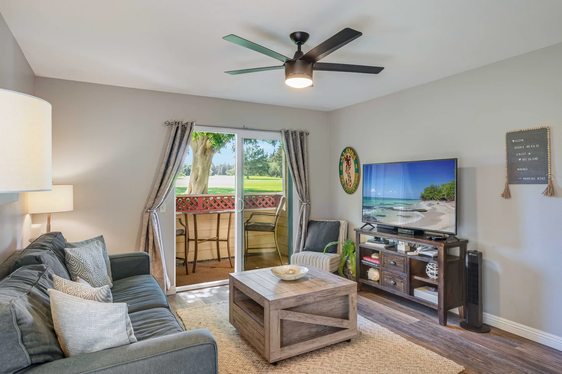 A living room with seating, a coffee table, and a television beside glass doors.