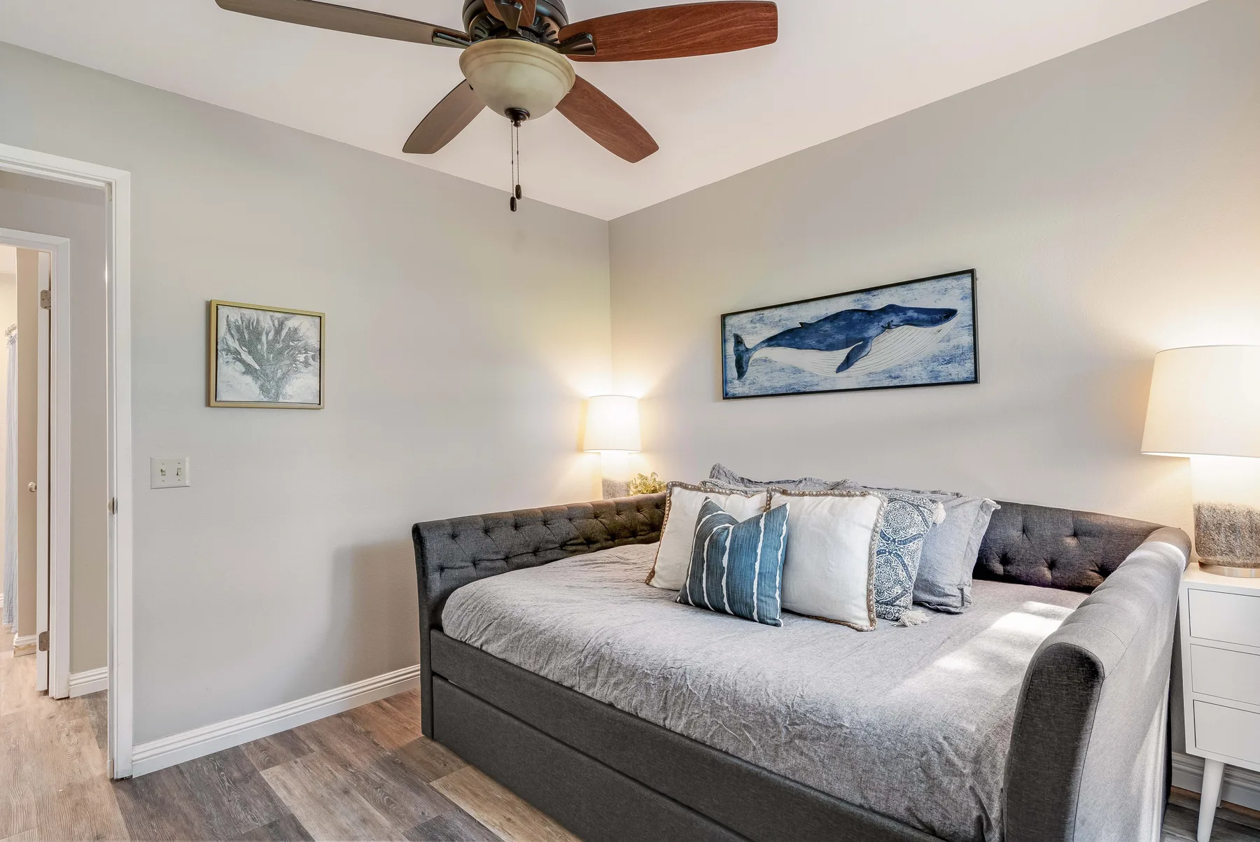 A bedroom with a large bed, decorative pillows, and framed wall art.