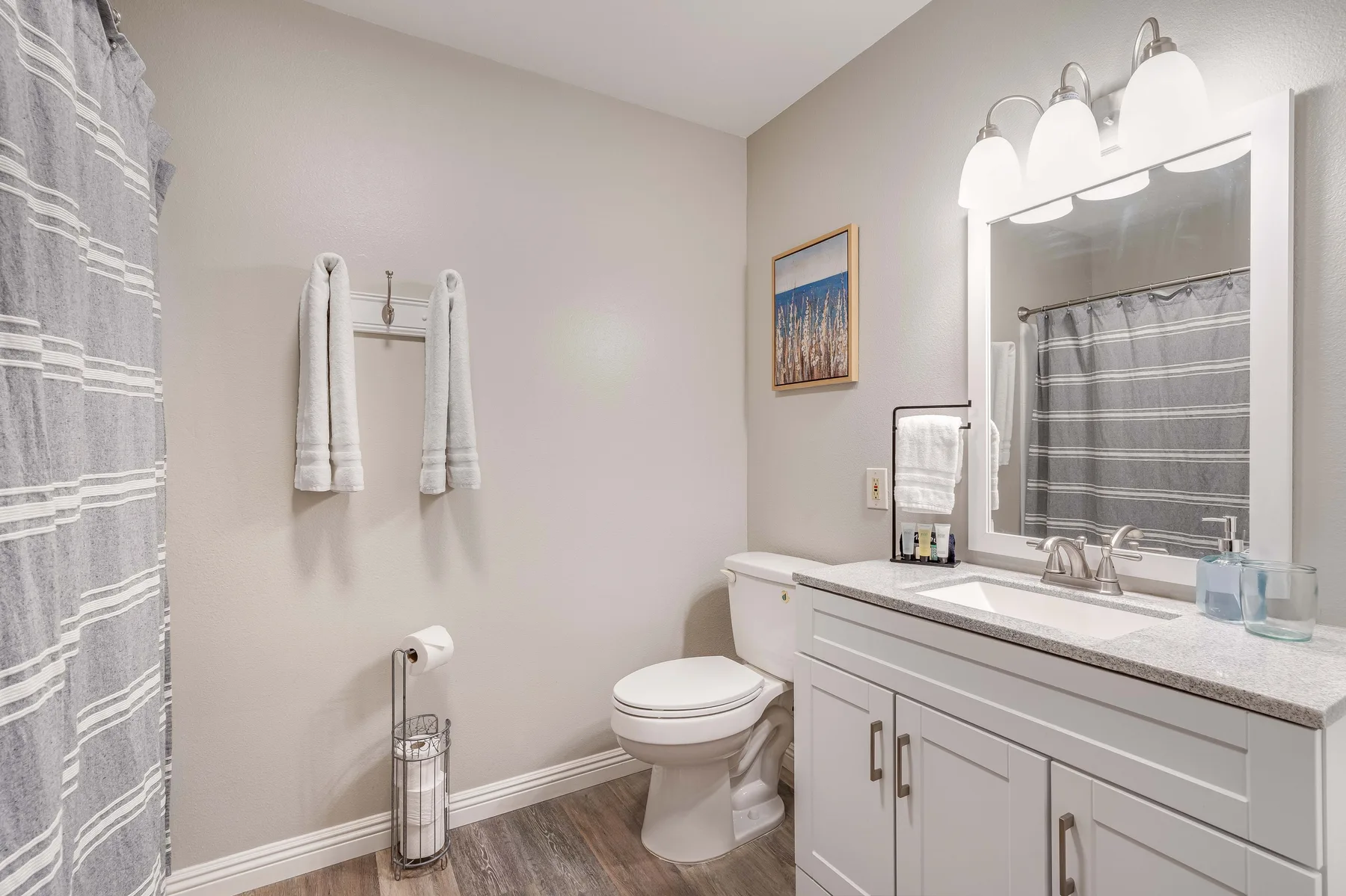 A bathroom with a toilet, vanity, and striped shower curtain.